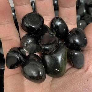 Polished black obsidian tumbled stones in palm for aquarium and garden decor