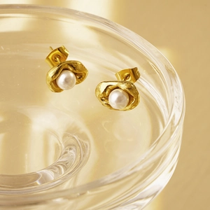 Elegant gold pea-shaped pearl earrings with irregular textured metal on glass edge