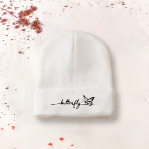 Bonnet en tricot blanc orné d'une broderie papillon noire et logo manuscrit