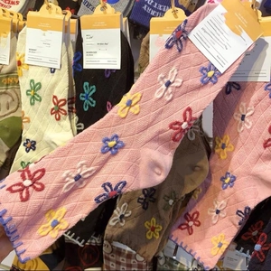 Detail of pink knitted mid-tube socks with 3D floral embroidery and diamond texture