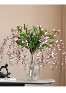 Detailed view of artificial weeping jasmine branches in a clear glass vase for home decor
