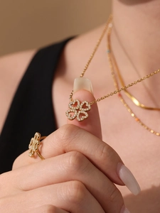 Dettaglio del set di collana e anello a quadrifoglio dorato con zirconi a cuore