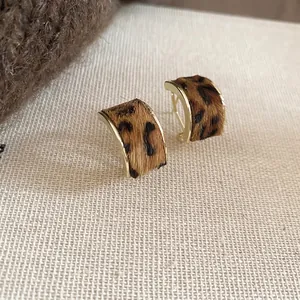 Retro leopard print C-shaped stud earrings with gold plating on beige linen background