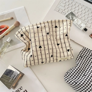 Détail de la trousse de maquillage beige à carreaux avec cœurs et étiquette tissée