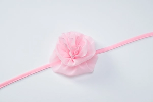 Detailed view of a pink mesh flower headband with an elastic band for baby girls