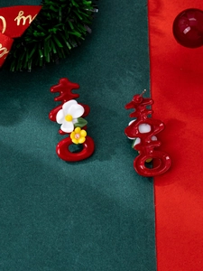 Macro detail of red festive earrings with囍 character and floral accents on dual background