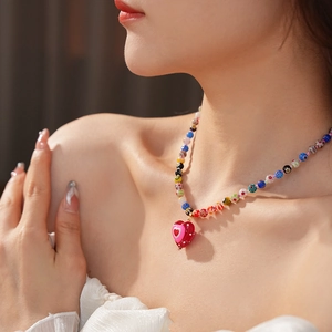 Close-up of a colorful beaded heart pendant necklace worn on a woman's collarbone