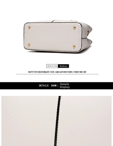 Detail view of white tote bag bottom with gold metal studs and black edge painting