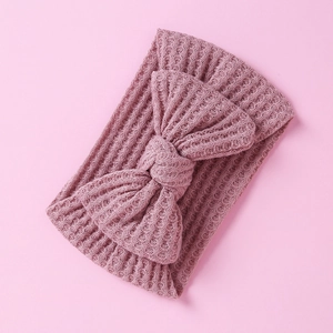 Close-up of purple knitted baby headband with large bow detail and mesh texture