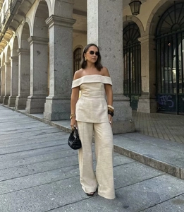 Detail of off-shoulder crop top and wide-leg linen trousers set in natural beige color
