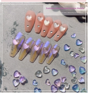 Macro detail of pearlescent 3D heart nail charms with aurora and cat-eye finish
