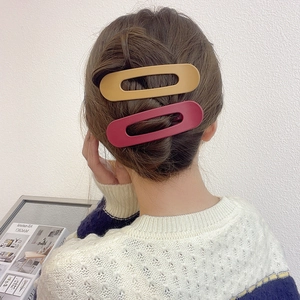Detail of large matte ginger and burgundy hollow hair clips used in an elegant updo