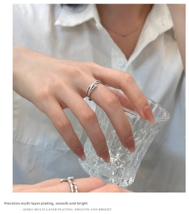 Detailed view of silver twist ring with zircons worn while holding a glass cup