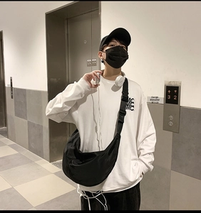Urban lifestyle view of a large black nylon crescent crossbody bag with adjustable strap