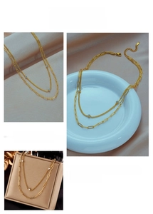 Dettaglio di collana a doppia catena dorata con pietre blu e maglie ovali su seta fine