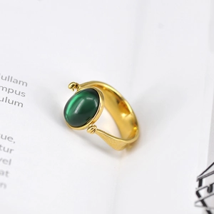 Retro Goldring mit ovalem grünem Edelstein und Katzenaugeneffekt auf weißem Papier
