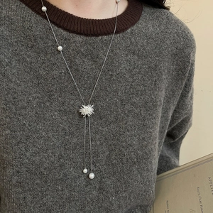 Détail du pendentif étoile en argent et des perles blanches sur collier long pour femme