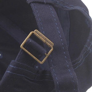 Detail of adjustable metal buckle and navy blue cotton fabric on a baseball cap