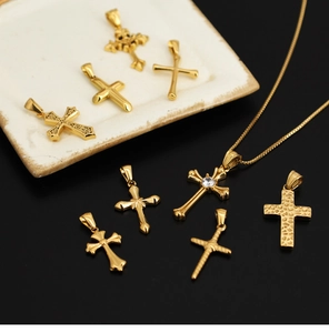 Golden titanium steel cross pendants with rhinestone details on a white ceramic tray