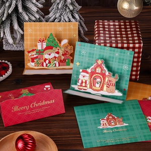 Close-up of 3D pop-up Christmas cards with gold foil and envelopes on wooden background