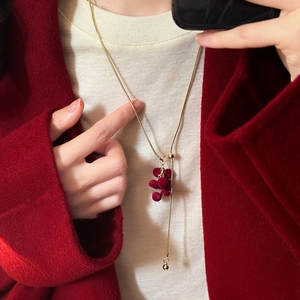 Y-shaped gold snake chain necklace featuring red flocked grape tassel and sliding bead