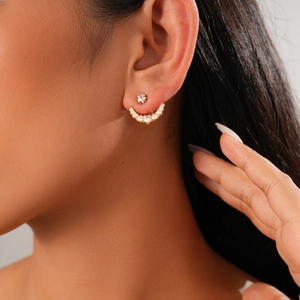 Detailed view of gold star-shaped stud earring with curved rhinestone crawler on ear