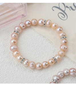 Dettaglio macro di perle barocche rosa naturali e distanziatori in strass sul braccialetto