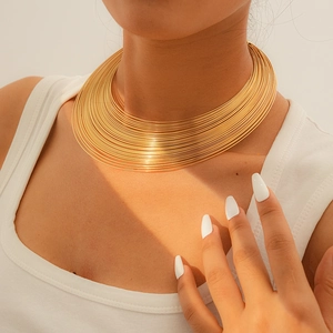 Nahaufnahme eines minimalistischen mehrlagigen Goldhalsreifs getragen von einem Model