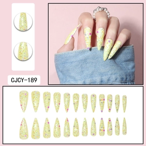 Macro detail of long stiletto press-on nails with yellow glitter and colorful sequins