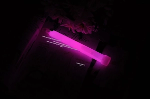 Pink glowing emergency glow stick with hook detail on an artistic dark background