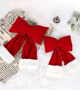 Detail of red velvet Christmas bows with faux fur pom poms on a festive background