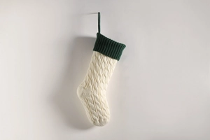 Detail of cable knit Christmas stocking in cream white with dark green ribbed cuff