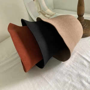 Détail de chapeaux cloches en feutre de laine rouge brique, noir et camel au style épuré
