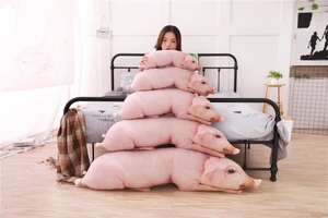 Cuscini di peluche a forma di maiale in cinque dimensioni impilati in una camera da letto.