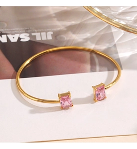 Detail of gold-plated open bangle featuring dual pink rectangular zircon stone settings