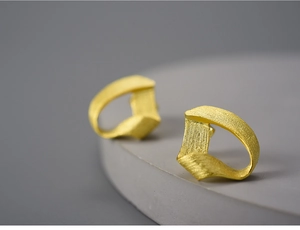Detailed macro view of gold-plated S925 silver stud earrings with a matte twisted texture