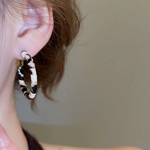 Close-up of leopard print hoop earring with gold accents worn by a model in detail