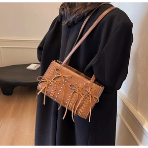 Detailed close-up of brown PU leather shoulder bag with woven texture and bow detail