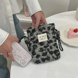 Détail du sac bandoulière en peluche léopard avec bandoulière nouée et étiquette arc-en-ciel