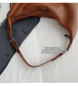 Detailaufnahme der braunen Umhängetasche aus genarbtem Leder mit Silberringen und Reißverschluss