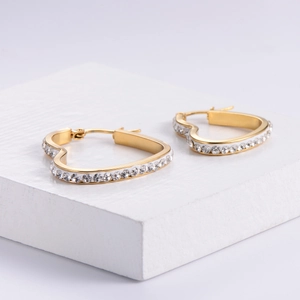 Elegant gold heart hoop earrings with sparkling rhinestones on a white geometric stand