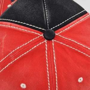 Detailed macro view of red and black baseball cap crown with reinforced white stitching