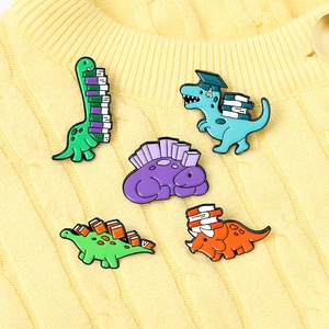 Detailed view of five cartoon dinosaur enamel pins with books and graduation caps