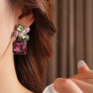 Close-up of vintage flower earrings with colorful crystals and pearl on a model