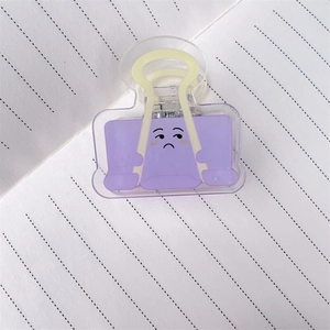Dettaglio della clip in acrilico viola con emoji triste su carta per appunti puntinata