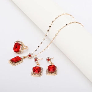 Close-up of gold jewelry set with red rectangle gemstones and clear rhinestones