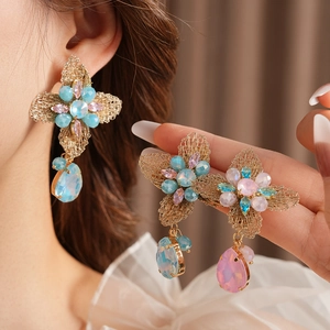 Detail of vintage flower earrings with multicolored crystals and gold woven wire petals