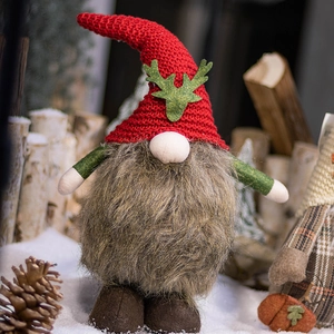Christmas gnome plush with red reindeer hat and grey beard standing in winter snow scene