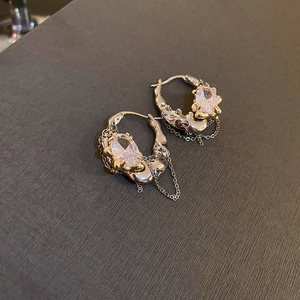 Macro shot of silver bow earrings with crystals, pearls, and long chain tassels