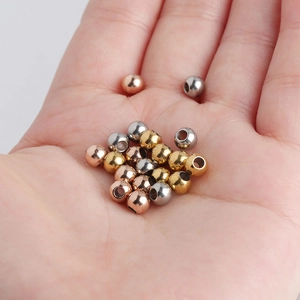 Macro view of 5mm stainless steel beads in gold, silver and rose gold held in hand